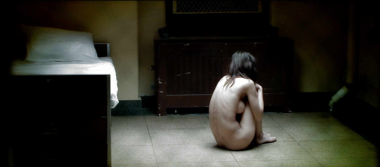 Mary sits alone on the floor of an institutional room